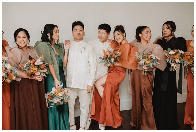 Wedding party in colorful attire with bouquets.