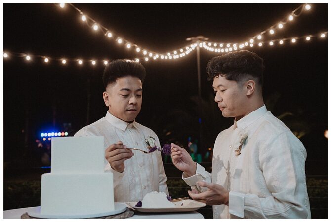 Two men sharing cake at wedding reception