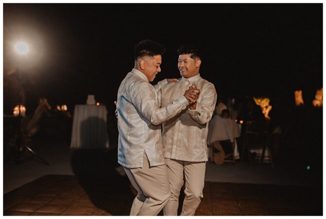 Couple dancing joyfully at a nighttime wedding.