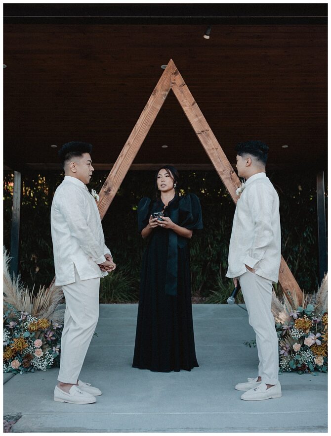 Wedding ceremony with couple and officiant under arch.