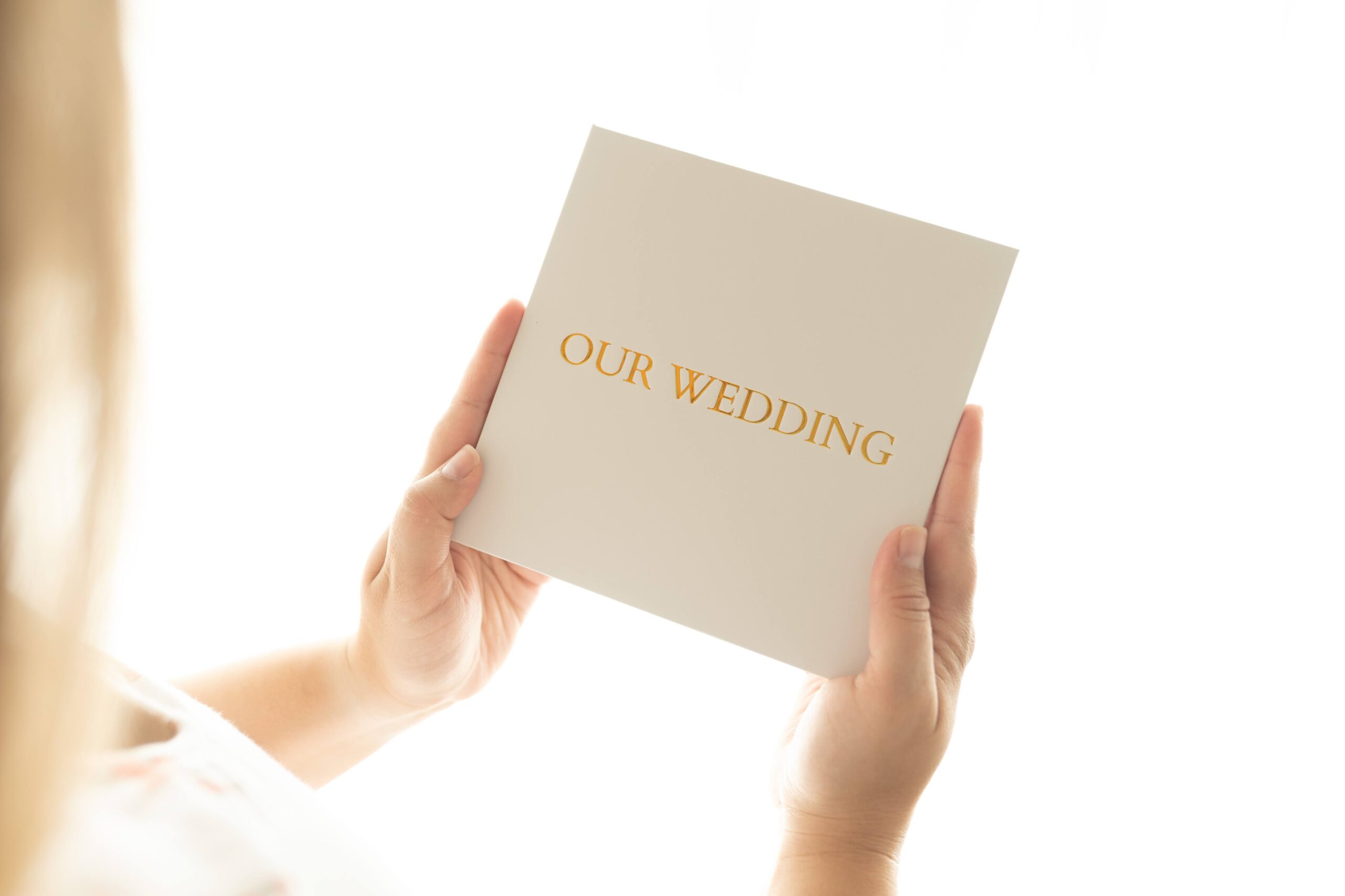 Person holding 'Our Wedding' invitation card