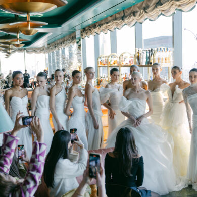 Models in white wedding dresses posing at event.